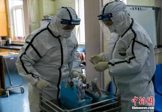 资料图:医院隔离病房内,两名医务人员核对患者药品。中新社记者 张畅 摄 湖北累计治愈出院4774例